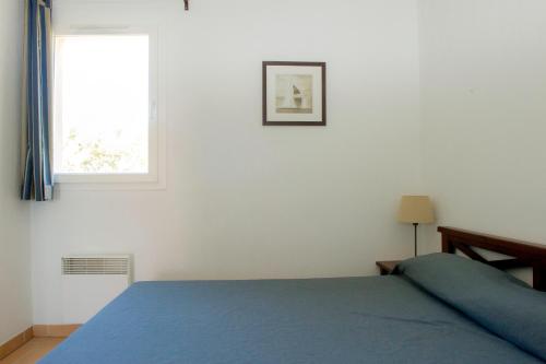 a bedroom with a blue bed and a window at Résidence Goélia Cap Bleu in Carro