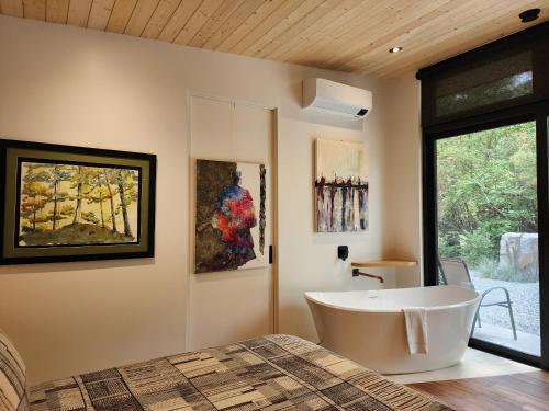 uma casa de banho com uma banheira grande e pinturas na parede em The Shed at Moon Dance em Madeira Park