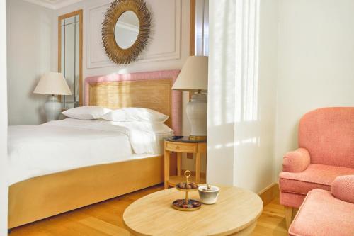 a bedroom with a bed and a chair and a table at Palmyard Hotel in Manama