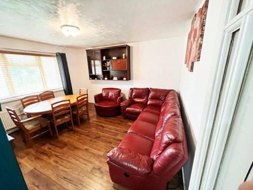 a living room with a red leather couch and a table at Beautiful House in Bournemouth in Longham