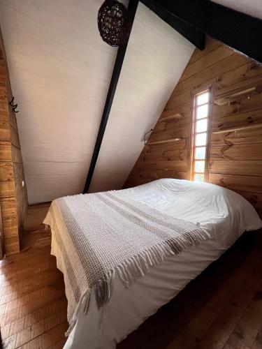 a bed in a wooden room with a window at Habitación cálida y acogedora a pasos del mar in Buchupureo