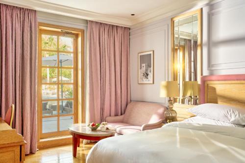 a bedroom with a bed and a chair and a window at Palmyard Hotel in Manama