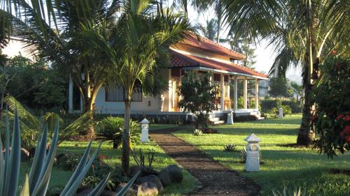 a house with palm trees in front of it at Rumah Kita Villa/hotel in Kalibaru