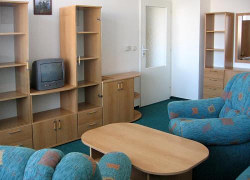 a living room with a tv and two chairs and a table at Hotel Morava in Jevíčko