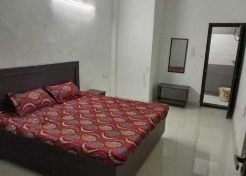 una camera da letto con un letto con un piumone rosso e uno specchio di OYO Hotel Kamal a Bharatpur