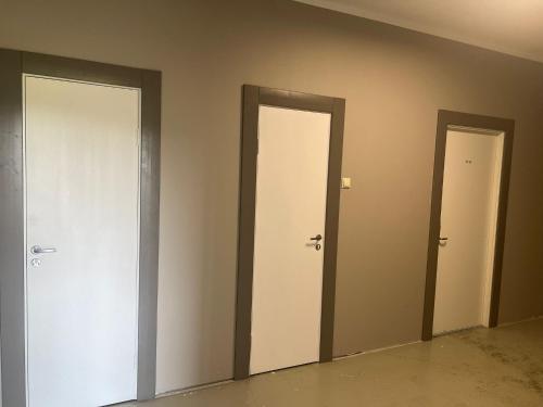 three doors in an empty room with at Worker hotel ALEJPARKS in Valmiera