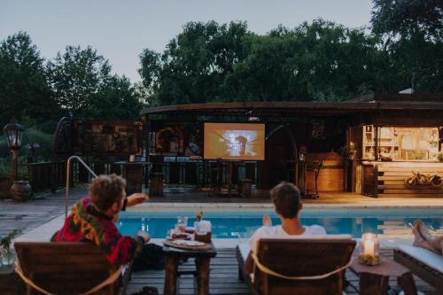 Un gruppo di persone sedute intorno a una piscina a guardare un film di Cabañas en el Bosque a 5 minutos del mar - Estancia CH a Punta del Este