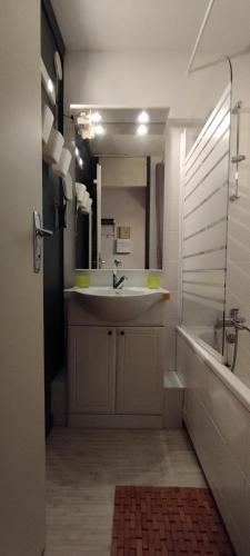 une salle de bain avec un lavabo, une baignoire et un miroir dans l'établissement Résidence le chalet des orres, aux Orres