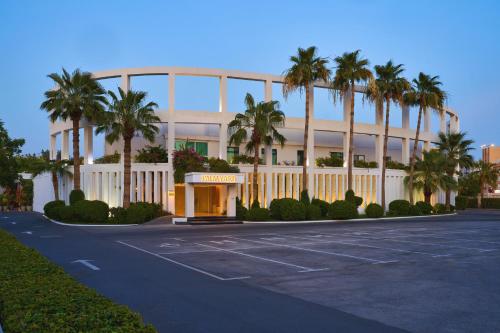 a parking lot in front of a building with palm trees at Palmyard Hotel in Manama