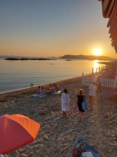 a group of people walking on the beach at sunset at Appartamento al mare di Liguria e Toscana in Marina di Massa