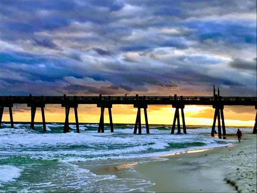 a pier over the ocean with a person walking on the beach at Waterfront Newly Renovated and Decorated 3brs home in Milton