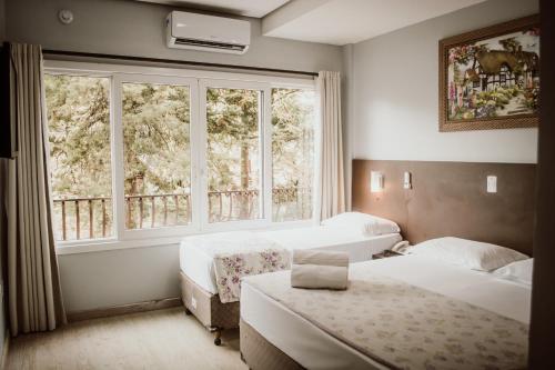 a bedroom with two beds and a window at Hotel Colina São Francisco in Gramado