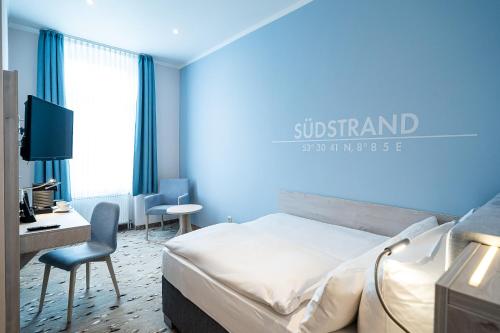 Wilhelms HAVEN HOTEL في فيلهلمسهافن: غرفة نوم بحائط ازرق مع سرير ومكتب
