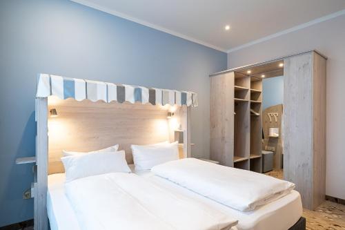 a bedroom with a large white bed and a mirror at Wilhelms HAVEN HOTEL in Wilhelmshaven