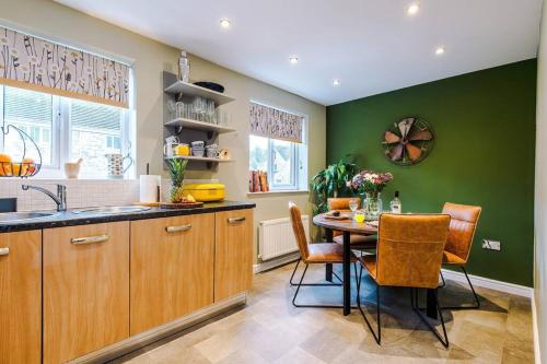a kitchen with green walls and a table and chairs at Luxury 3-bed house - Rothwell Gardens - 10mins from Leeds city centre in Rothwell