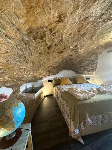 a room with a bed and a bathtub in a cave at Tajito Romano in Setenil