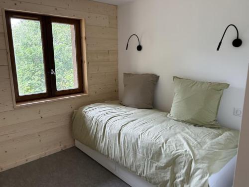 a bed in a room with a window at Chalet la parenthèse in Le Tholy