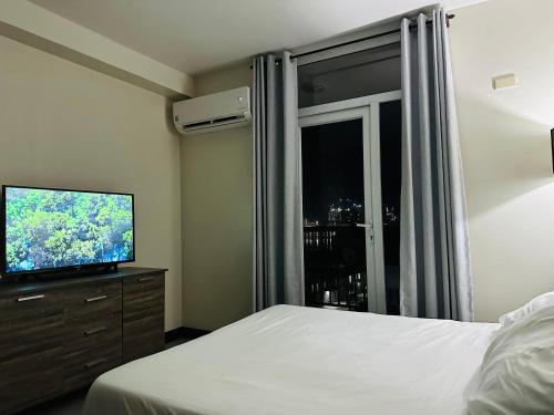 Seaview Sunset Accommodation في مدينة سيبو: غرفة نوم بسرير وتلفزيون بشاشة مسطحة