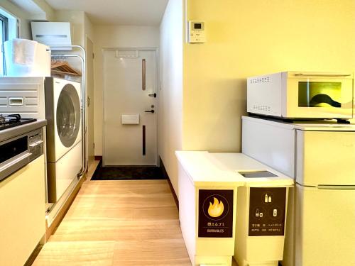 a kitchen with a microwave and a box on the floor at 上野レトロ花 2-4人和風寝室 山手線3分 上野浅草銀座近い 御徒町駅3分 アメ横3分 上野駅10分 上野広小路駅3分 湯島駅2分 空港直接 in Tokyo