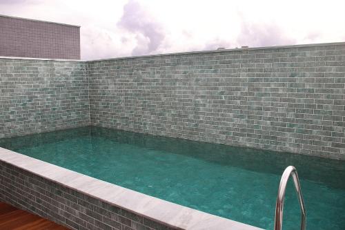 ein großer Swimmingpool mit einer Ziegelmauer und blauem Wasser in der Unterkunft Park Del Prado #603 - Intermares por Carpediem in Cabedelo