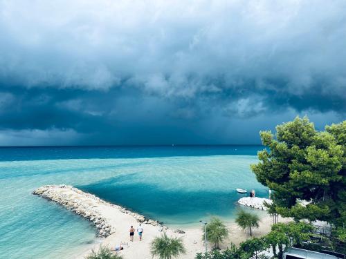 a group of people walking on a beach in the ocean at Apartmani Mutogras in Podstrana