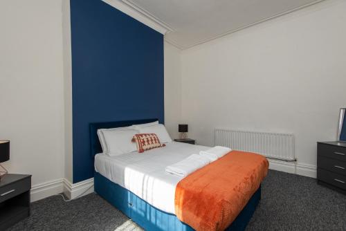 a bedroom with a bed with a blue wall at Rose Street in Monkwearmouth