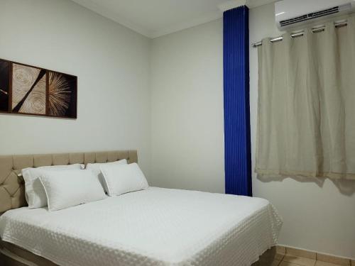 a bedroom with a bed with white sheets and a window at Madeira Lofts - Suite 01 in Juína