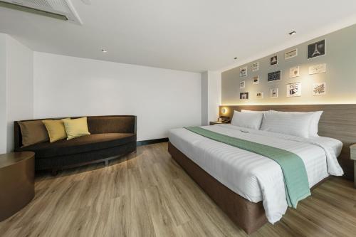 a hotel room with a large bed and a couch at Golden Tulip Mandison Suites in Bangkok