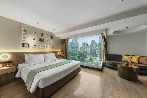 a bedroom with a large bed and a large window at Golden Tulip Mandison Suites in Bangkok