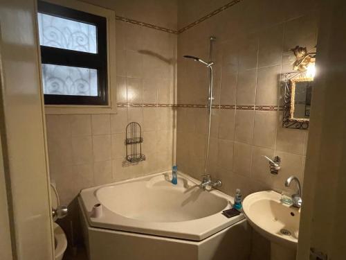 a bathroom with a tub and a sink and a window at Relaxing Gem in Downtown in Cairo