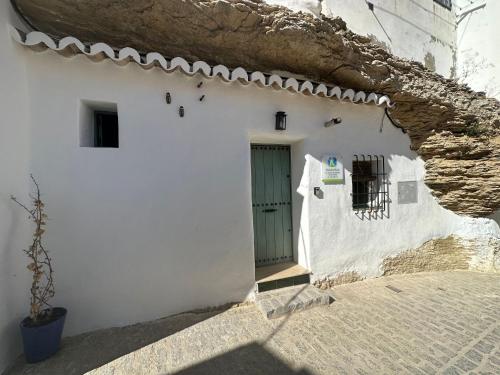ein weißes Gebäude mit einer Tür und einer Wand in der Unterkunft Tajito Romano in Setenil de las Bodegas
