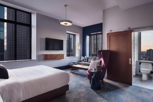 una camera da letto con un letto, un divano e una TV di Rand Tower Hotel, Minneapolis, a Tribute Portfolio Hotel a Minneapolis