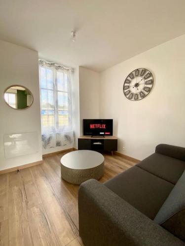 a living room with a couch and a clock on the wall at LOFT Jardin et Spa in Bressuire