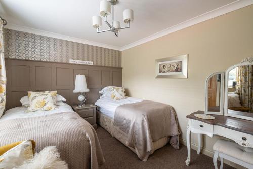 a bedroom with two beds and a desk and a mirror at Esk View in Whitby