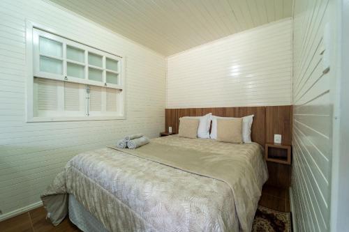 a bedroom with a large bed with a window at Chalés da Tribo in Bom Jardim da Serra