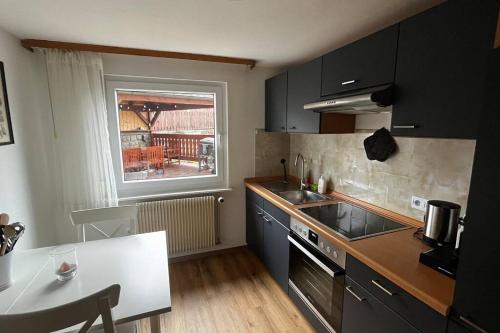 een keuken met zwarte kasten en een tafel en een raam bij Gemütliche Wohnung in Häusern in Häusern
