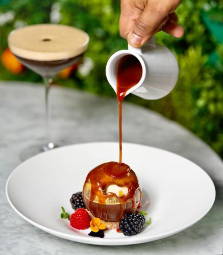 a person pouring sauce onto a dessert on a plate at Sloane Place in London