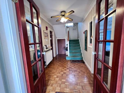 a hallway with a ceiling fan and a staircase at All Seasons Gatwick Guest House & Parking in Horley