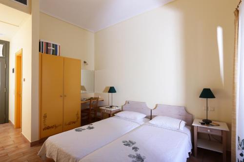 a bedroom with a white bed and a yellow cabinet at Eleonas hotel in Rovies