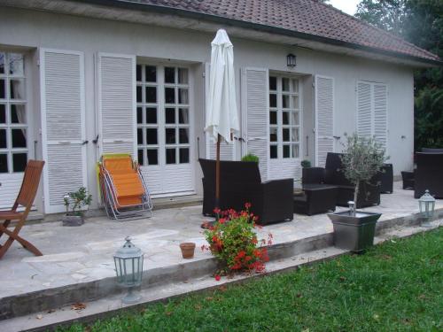 um pátio com um guarda-sol, cadeiras e uma mesa em La Petite Trolière em Orval