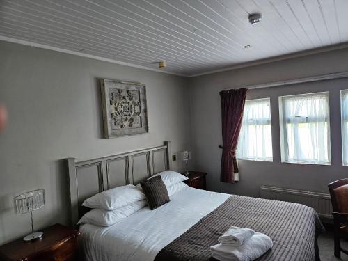 a bedroom with a bed and two windows at Pennine Manor Hotel in Huddersfield