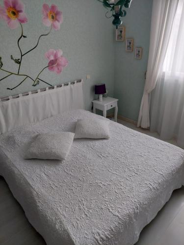ein Schlafzimmer mit einem weißen Bett mit rosa Blumen an der Wand in der Unterkunft Villa Machilly in Machilly