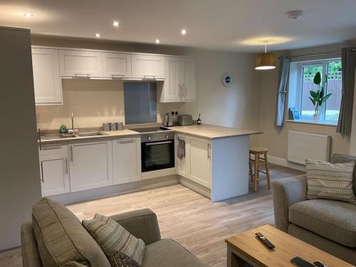 a kitchen with white cabinets and a living room at Beautiful Holiday Cottage in Ashbourne