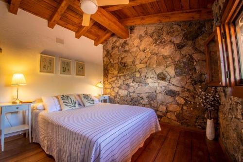 a bedroom with a bed and a stone wall at Casa Mimosa in Candeleda