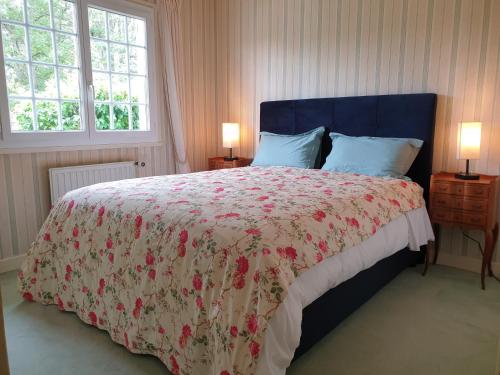 1 Schlafzimmer mit einem Bett mit Blumenbettdecke und 2 Fenstern in der Unterkunft Charmante propriété, piscine, Zoo Beauval, Châteaux Loire in Selles-sur-Cher