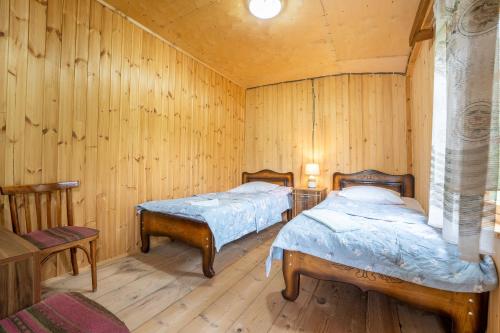 two beds in a room with wooden walls at GuestHouse NaSHGOBI in Ushguli