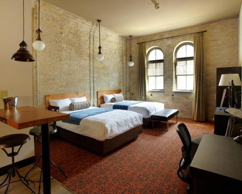 a bedroom with two beds and a table and a desk at Brewhouse Inn and Suites in Milwaukee