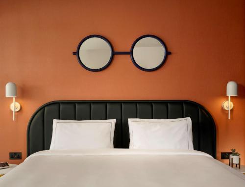 a bedroom with a bed with two mirrors on the wall at art'otel London Battersea Power Station, Powered by Radisson Hotels in London