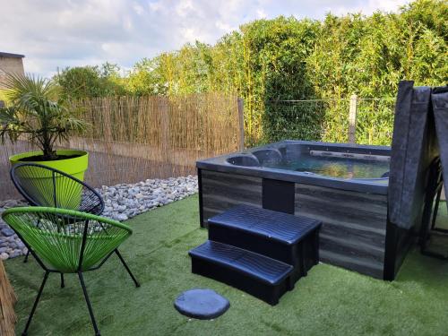 patio trasero con bañera de hidromasaje, silla y mesa en La Maison d'Equilly, en Équilly