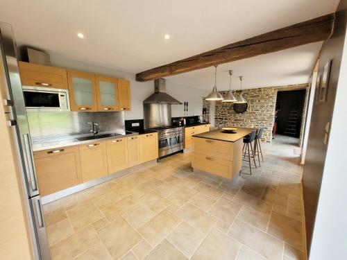 cocina grande con armarios de madera y mesa en La Maison d'Equilly en Équilly